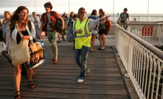 Une bénévole donne des instructions aux vacanciers de Lège-Cap-Ferret à leur arrivée à Arcachon par bateau, lors d'une opération d'évacuation de l'ensemble de la presqu'île du Cap-Ferret, dans le sud-ouest de la France, le 24 juillet 2026
