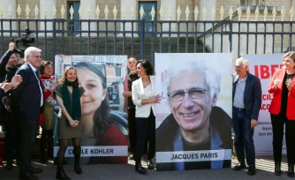 Cécile Kohler (3e G) et Jacques Paris (2e D) devant leurs portraits décrochés des grilles de l'Assemblée nationale, à Paris le 14 avril 2026