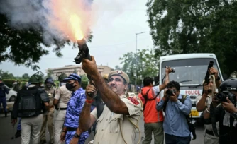 Un policier tire des grenades lacrymogĂšnes pour disperser des militants du "Parti du peuple des cafards" (CJP) lors d'une manifestation rĂ©clamant la dĂ©mission du ministre de l'Ăducation, Dharmendra Pradhan, en raison de fraudes prĂ©sumĂ©es aux examens universitaires, le 20 juillet 2026 Ă New Delhi, en Inde