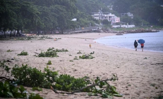 Des personnes se promènent sur une plage jonchée de débris laissés par le typhon Noul, à Hong Kong, le 26 juillet 2026