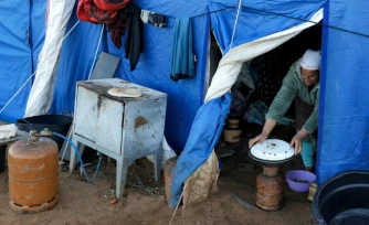 Une femme prépare à manger dans l'une des tentes d'un camp destiné aux personnes touchées par les inondations qui ont frappé le nord et l'ouest du Maroc, dans la région de Kénitra, le 20 février 2026