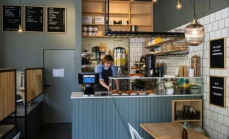 Kajetan Grzelczak derrière son comptoir  au café Andon à Stockholm, entièrement dirigé par l'IA, le 27 avril 2026