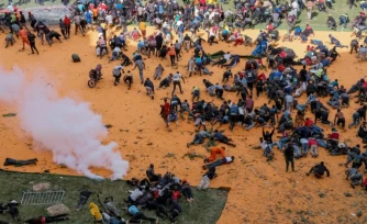 Des partisans et personnes en deuil se mettent à l'abri après que des coups de feu et des gaz lacrymogènes ont été tirés lors d'un rassemblement pour l'exposition publique du cercueil du leader de l'opposition kenyan Raila Odinga au stade Kasarani à Nairobi, le 16 octobre 2025, au lendemain de son décès en Inde