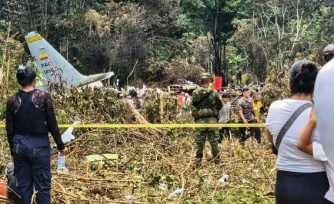 Des civils et des militaires se tiennent près des débris d'un Hercules de l'armée de l'air colombienne qui s'est écrasé au décollage à Puerto Leguizamo, en Colombie, le 23 mars 2026