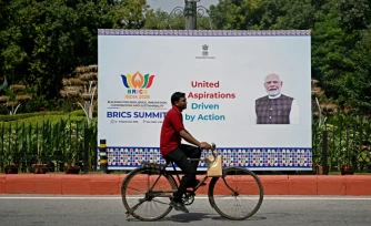 Un cycliste passe devant un panneau montrant le Premier ministre indien Narendra Modi, installé en amont du sommet des Brics, à New Delhi, le 9 septembre 2026