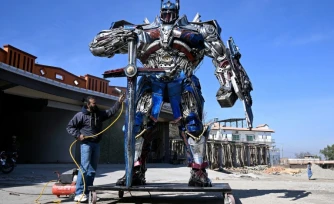 Le sculpteur Ehtisham Jadoon à cÎté de son Optimus Prime, personnage du film Transformers, fabriqué à partir de ferraille devant son atelier situé à la périphérie d'Islamabad, le 12 février 2026 au Pakistan