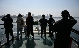Des touristes observent la ville nord-coréenne de Sinuiju (arriÚre-plan) depuis un bateau touristique sur le fleuve Yalu, dans la ville frontaliÚre de Dandong, dans le nord-est de la Chine, le 26 mars 2026