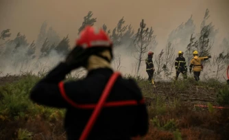 Des pompiers arrosent la lisière d'une forêt lors d'un incendie de forêt près de la ville de Lège-Cap-Ferret, en Gironde, le 25 juillet 2026