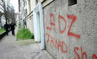 Des policiers patrouillent à proximité d'un mur avec un tag DZ désignant la DZ mafia à Avignon le 13 mars 2025