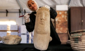 Une membre de l'association Mayasem pour la culture et les arts nettoie un artefact à la brosse, sous une tente à Khan Younès, dans le sud de la bande de Gaza, le 11 juillet 2026
