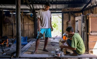Le noble Umbu Ana Rara (g) regarde son esclave (d) Kanisius Kanyali Hambarita préparer des boissons au village de Tanggedu, dans l'est de l'ßle de Sumba, le 23 juin 2026 en Indonésie