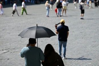 Des touristes visient Bruxelles à l'abri sous un parapluie pour se protéger du soleil lors d'une vague de chaleur le 27 mai 2026, en Belgique