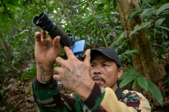 Octavius, villageois indonésien et ancien braconnier, utilise un téléphone portable équipé d’un téléobjectif pour prendre des photos d’animaux sauvages dans une forêt près du village de Labian, à Kapuas Hulu, à Bornéo, le 2 septembre 2026