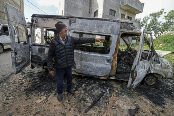 Un Palestinien à proximité d'un véhicule calciné après une attaque attribuée à des colons israéliens à Jalud, près de Naplouse, en Cisjordanie occupée, le 22 mars 2026