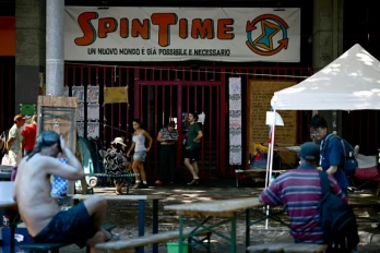 Des personnes récemment expulsées d'un centre social à Rome sont installées devant ses grilles fermées, le 11 août 2026