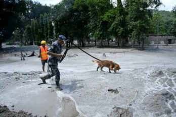 Un membre des forces de sécurité et son chien recherchent des survivants à la suite des inondations à Trishuli au Népal, le 27 août 2026