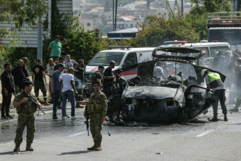 Des secouristes autour d'un véhicule ciblé par une frappe de drone israélien sur une autoroute près de la ville de Jiyeh, au sud de Beyrouth, le 13 mai 2026 au Liban