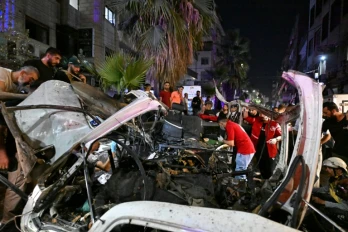 Des passants et des secouristes inspectent la carcasse du minibus dans lequel une bombe a explosé, à Jaramana, près de la capitale syrienne, Damas, le 6 août 2026
