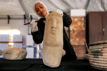 Une membre de l'association Mayasem pour la culture et les arts nettoie un artefact à la brosse, sous une tente à Khan Younès, dans le sud de la bande de Gaza, le 11 juillet 2026