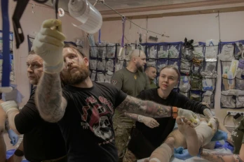 Anastassia Podobailo (d), son collègue et époux Mykola Iassinenko (2e g) et d'autres médecins militaires, soignent un soldat blessé dans un poste médical de la 56e brigade, dans la région de Donetsk, le 15 mars 2026 en Ukraine