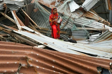 Une jeune fille parmi les débris de sa maison le 28 mai 2024 à Patuakhali au Bangladesh après le passage du cyclone Remal
