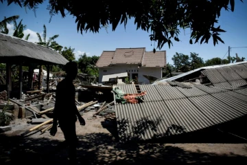 Un homme marche près d'un bâtiment effondré dans le village de Sugian sur l'île indonésienne de Lombok secouée par une série de séismes, le 20 août 2018