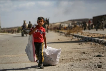 Un garçon palestinien porte un sac et traîne un autre derrière lui alors qu'il revient d'un point de distribution alimentaire dans le centre de la bande de Gaza, le 5 octobre 2025 ( AFP / Eyad BABA )