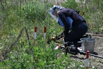 Tetiana Chpak, démineuse pour l'organisation Halo Trust, accroupie dans un champ près du village de Snigurivka, dans la région de Mykolaïv, le 4 juin 2024 en Ukraine