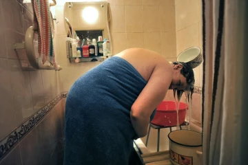 Une femme se lave les cheveux avec de l'eau qu'elle a chauffée le 7 juillet 2016 à Saint-Pétersbourg à cause des coupures traditionnelles d'eau chaude en été
