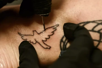 Scout Frank se fait tatouer une colombe par Kat Dukes avec de l'encre mélangée aux cendres funéraires de sa mère, le 6 octobre 2023 à Oceanside, en Californie ( AFP / Patrick T. Fallon )