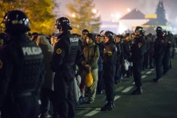 Des policiers slovènes encadrent les migrants sur le point de monter dans un bus le 28 octobre 2015 à Sentilj 