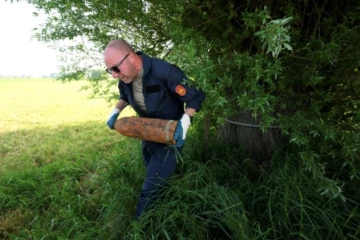Un membre de l'équipe de déminage de la DOVO ramasse de vieux obus de la Première Guerre mondiale trouvés dans la campagne du nord-ouest de la Belgique, près d'Ypres, le 19 mai 2025 ( AFP / Nicolas TUCAT )
