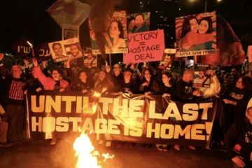 Des Israéliens tiennent des pancartes et allument des bougies lors d'une manifestation antigouvernementale appelant à agir pour obtenir la libération des otages israéliens à Gaza, devant le ministère de la Défense à Tel-Aviv le 18 janvier 2025 ( AFP / Jack GUEZ )