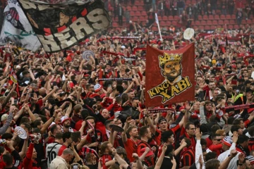 Les supporters du club de football du Bayer Leverkusen célèbrent la victoire de leur club en championnat d'Allemagne après sa victoire 5-0 contre le Werder Brême au stade de Leverkusen le 14 avril 2024.
