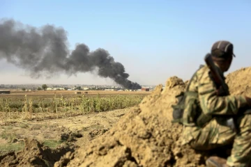 Un combattant syrien proturc regarde au loin la fumée s'élever de la ville frontalière de Ras al-Aïn, dans le nord de la Syrie, bombardée par les forces turques, le 12 octobre 2019