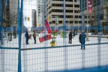Une poignée de manifestants derrière l'imposant grillage qui les sépare du Parlement, à Ottawa, le 20 février 2022