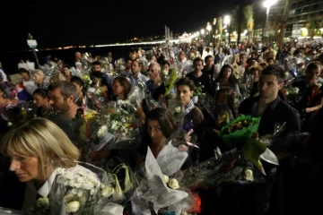 Une chaîne humaine déplace les bouquets déposés sur la Promenade des Anglais en hommage aux victimes de l'attentat du 14 juillet vers le front de mer à Nice le 18 juillet 2016