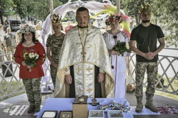 Des couples de militaires ukrainiens, Kristina et Vitali Orlich (à droite), ainsi que Kristina Liouta et Volodymyr Mikhalchouk (à gauche), pendant leur cérémonie de mariage dans la ville de Droujkivka, dans l'est de l'Ukraine, le 12 juin 2022