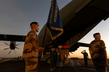 Les cercueils recouverts du drapeau aux couleurs de la France, près d'un soldat brandissant un étendard portant la mention "Opération Barkhane", avant d'être embarqués dans le gros porteur. Photo prise le 30 novembre 2019 et fournie le 1er décembre 2019 par le service de presse des armées Sirpa