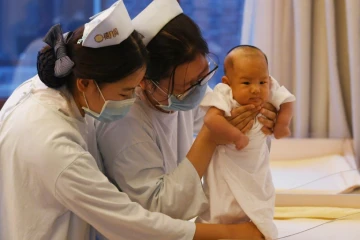 Des infirmières chinoises prennent soin d'un bébé pendant que sa mère se repose, au centre Xiyuege ("Foyer du mois de la chance") à Pékin, le 13 décembre 2016