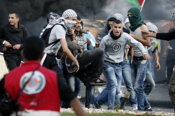 Des Palestiniens emmènent un camarade blessé à la jambe lors de heurts avec les forces de sécurité israéliennes, le 9 octobre 2015 à Ramallah