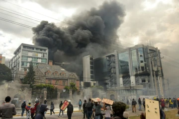 Des manifestants encagoulés mettent le feu au bureau de l'Inspection générale des finances, dans le nord de Quito, le 12 octobre 2019