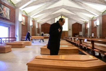 Le prêtre de la paroisse de Seriate, Don Mario, s'incline devant l'un des cercueils entreprosés dans l'église de sa commune, située près de Bergame, dans le nord de l'Italie, le 26 mars 2020