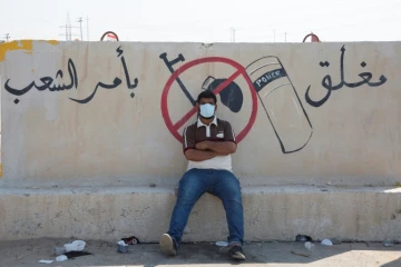 Un manifestant se repose près d'un muret où un slogan antigouvernemental a été inscrit, à Oum Qasr, dans le sud de l'Irak, le 3 novembre 2019
