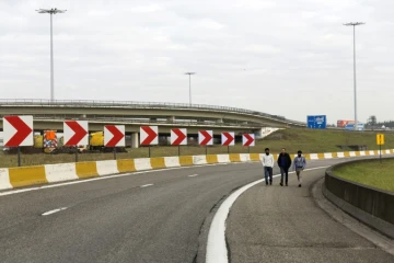 Des gens marchent sur une autoroute à la circulation fermée menant à l'aéroport de Bruxelles le 22 mars 2016