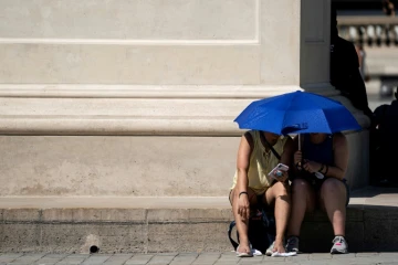 Des personnes se protègent du soleil près de la Pyramide du Louvre, à Paris le 26 juin 2019
