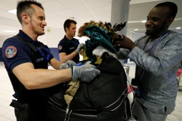Un douanier aide un passager à refaire son sac après une fouille à l'aéroport Roissy-Charles-de-Gaulle, le 26 juillet 2016