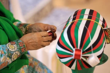 Une femme tresse des fils selon la méthode Al Talli, une technique de tissage locale traditionnelle, à Al-Ain, aux Emirats arabes unis, le 10 novembre 2023