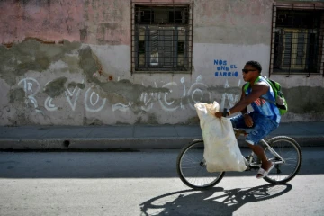 Un homme passe en vélo devant un graffiti "Revolucion" à Santiago de Cuba, le 31 décembre 2018