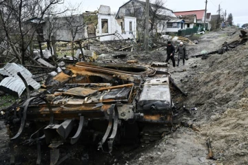 Des habitants passent près d'un tank russe détruit dans le village de Zalissya (Ukraine), au nord-est de Kiev, le 19 avril 2022